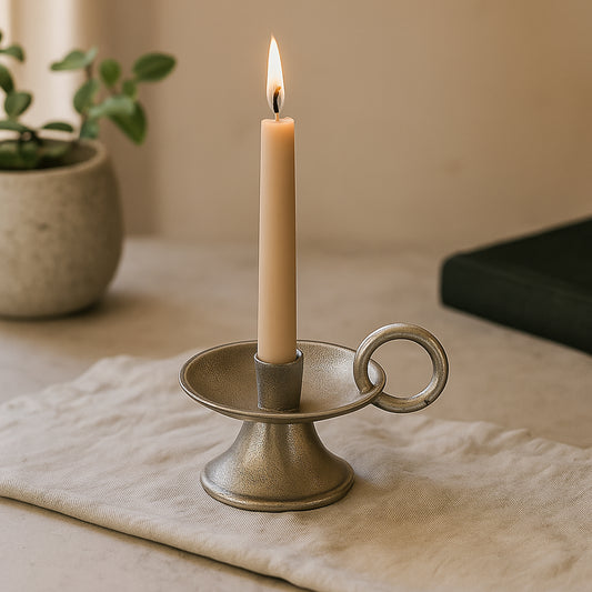 Candle in a decorative holder on a table with a plant in the background