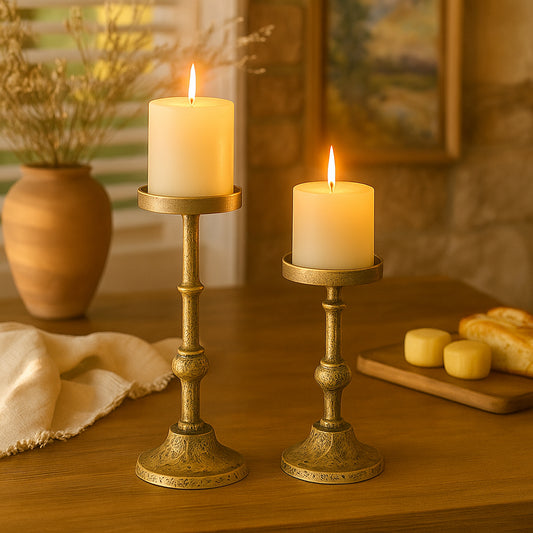 Two lit candles in decorative brass candlesticks on a wooden surface with a soft background.