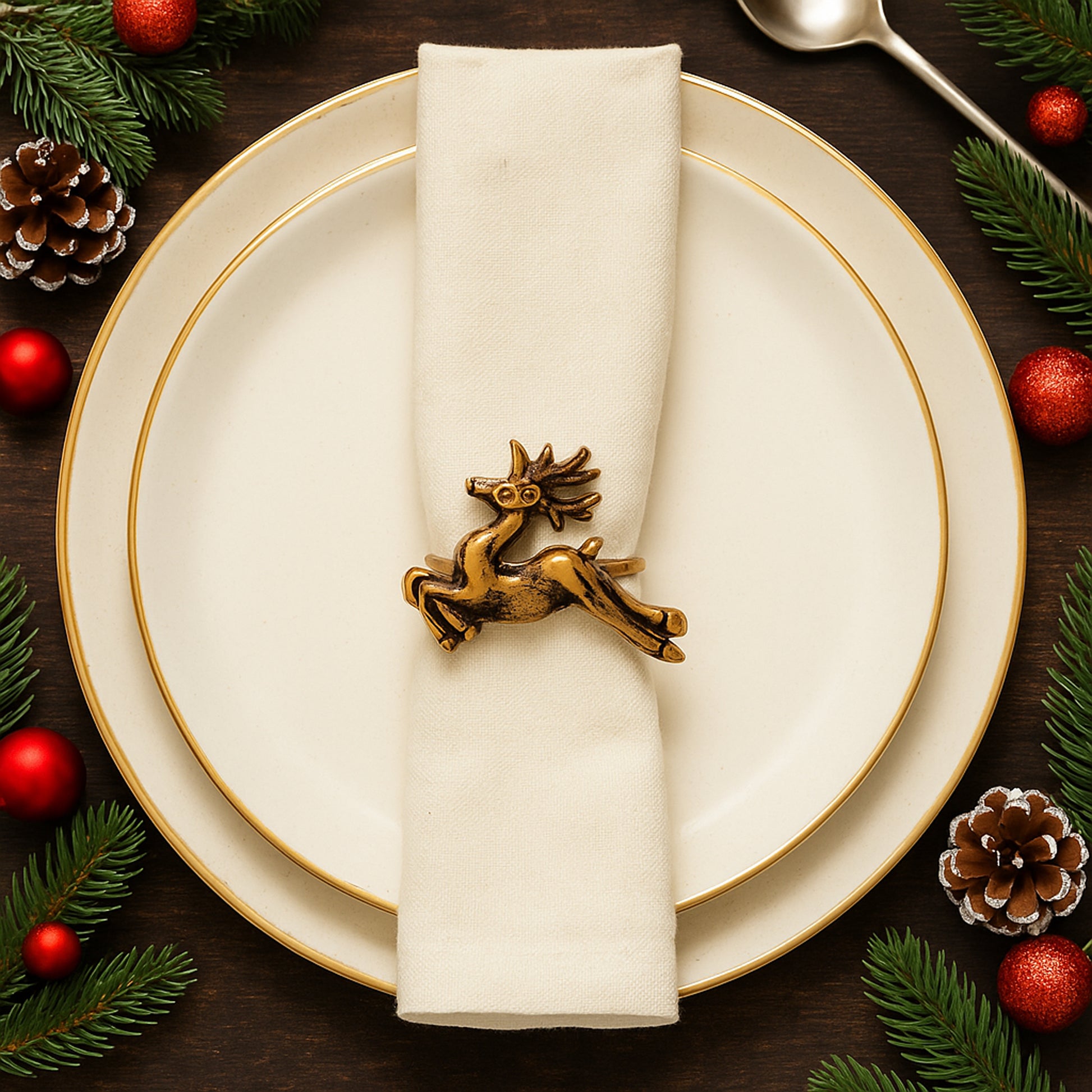 Christmas-themed table setting with gold reindeer napkin ring on a white plate.