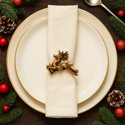 Christmas-themed table setting with gold reindeer napkin ring on a white plate.